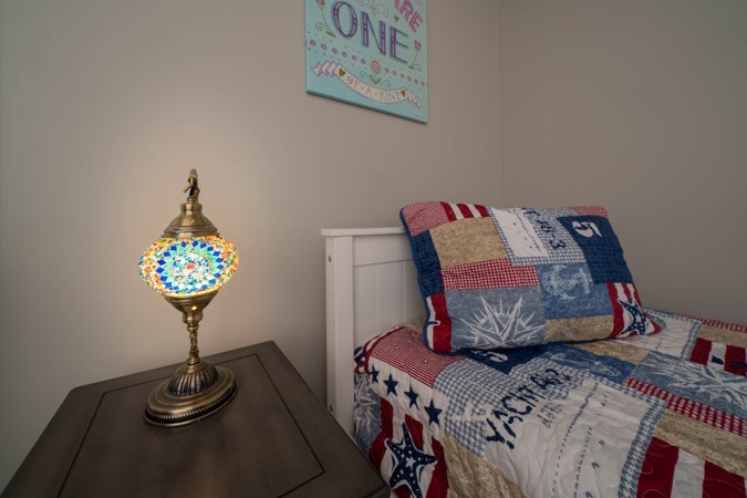 Twin bed with a nautical quilt and a mosaic lamp