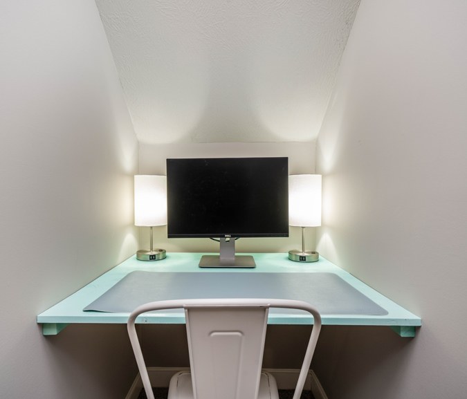 Dedicated workspace with a desk, monitor and lamps