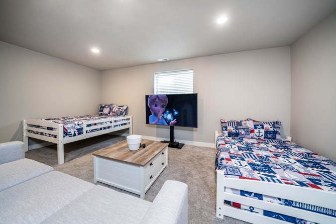 Basement family room with two twin beds, a couch and a TV