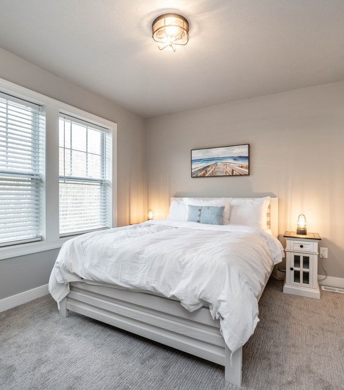 Bedroom with a white bed and a beach painting