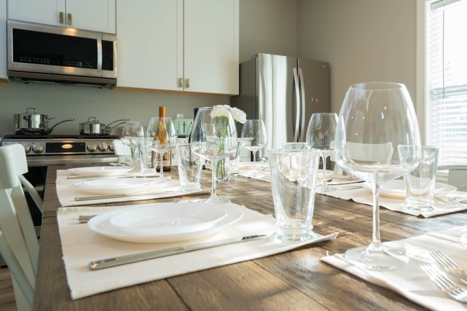 Dining table set for a meal, with the kitchen behind